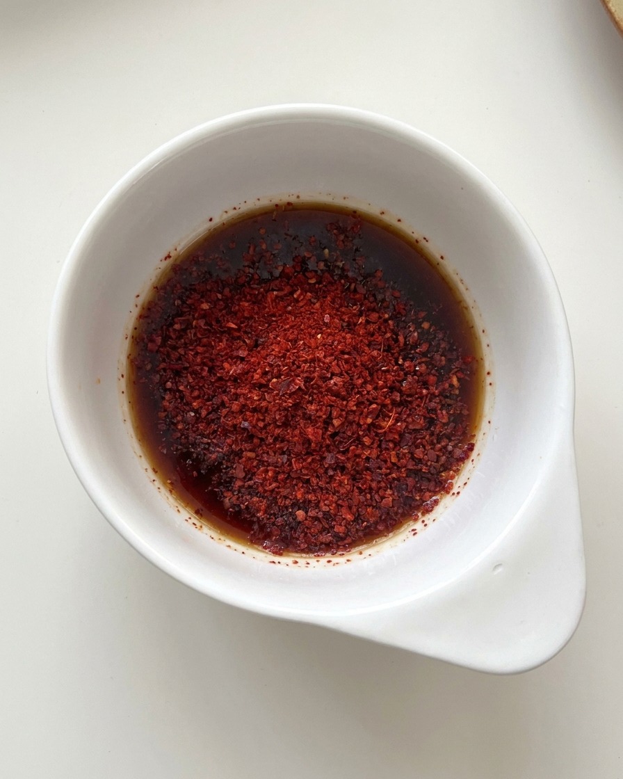 Cuenco blanco con una mezcla de salsa de soja oscura y chile rojo brillante en polvo.