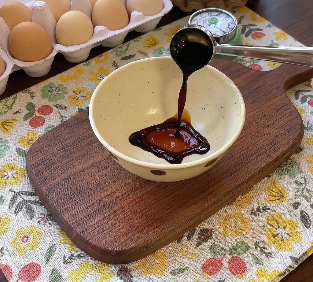 Salsa oscura vertiéndose en un bol con otros condimentos para aderezar una hamburguesa.