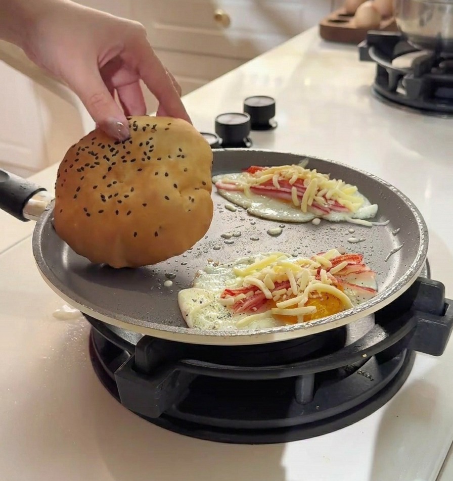 Mano colocando un pan tierno sobre el huevo con cangrejo y queso fundido.