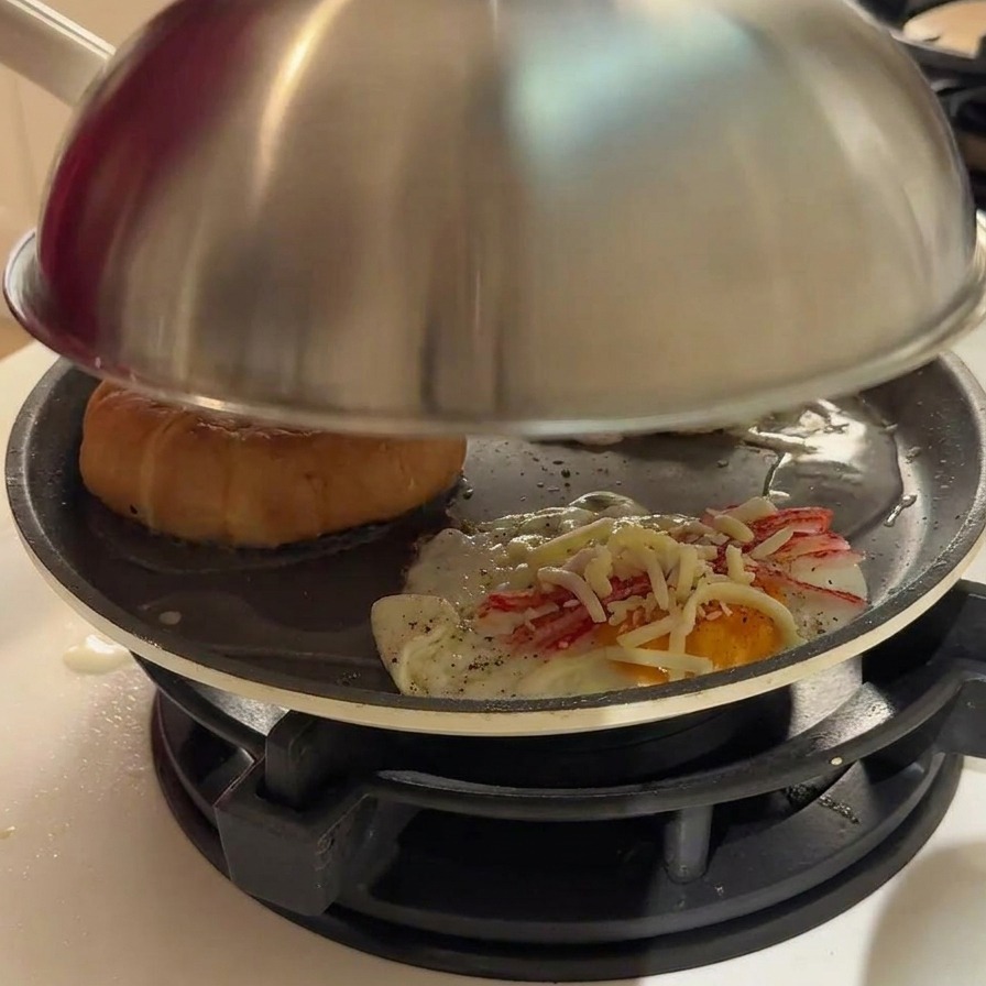 Vapor saliendo por los bordes de una tapa de metal sobre la sartén.