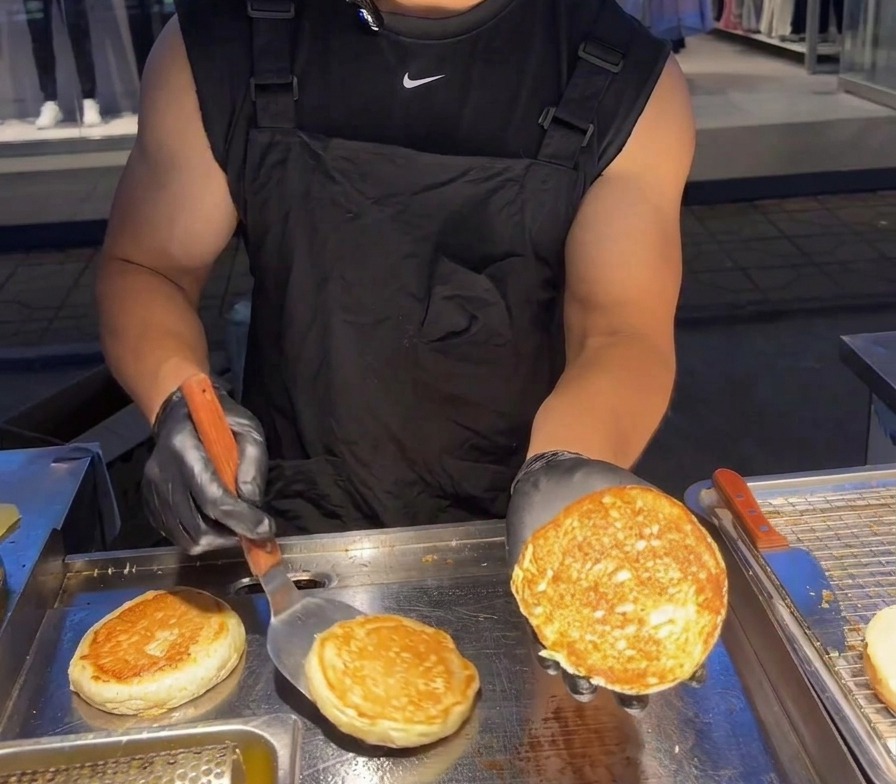 Una persona mostrando la superficie dorada y crujiente de la mitad de un pan de hamburguesa tostado.