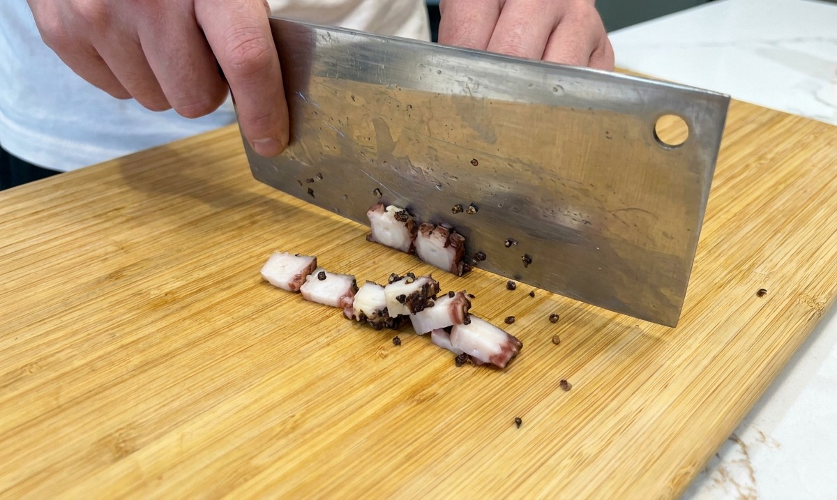 Cortar el guanciale en dados pequeños con un cuchillo sobre una tabla de madera.