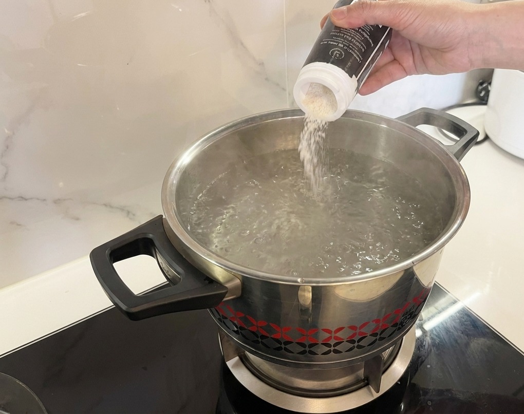 Sal vertiéndose desde un salero en una olla con agua hirviendo a borbotones.