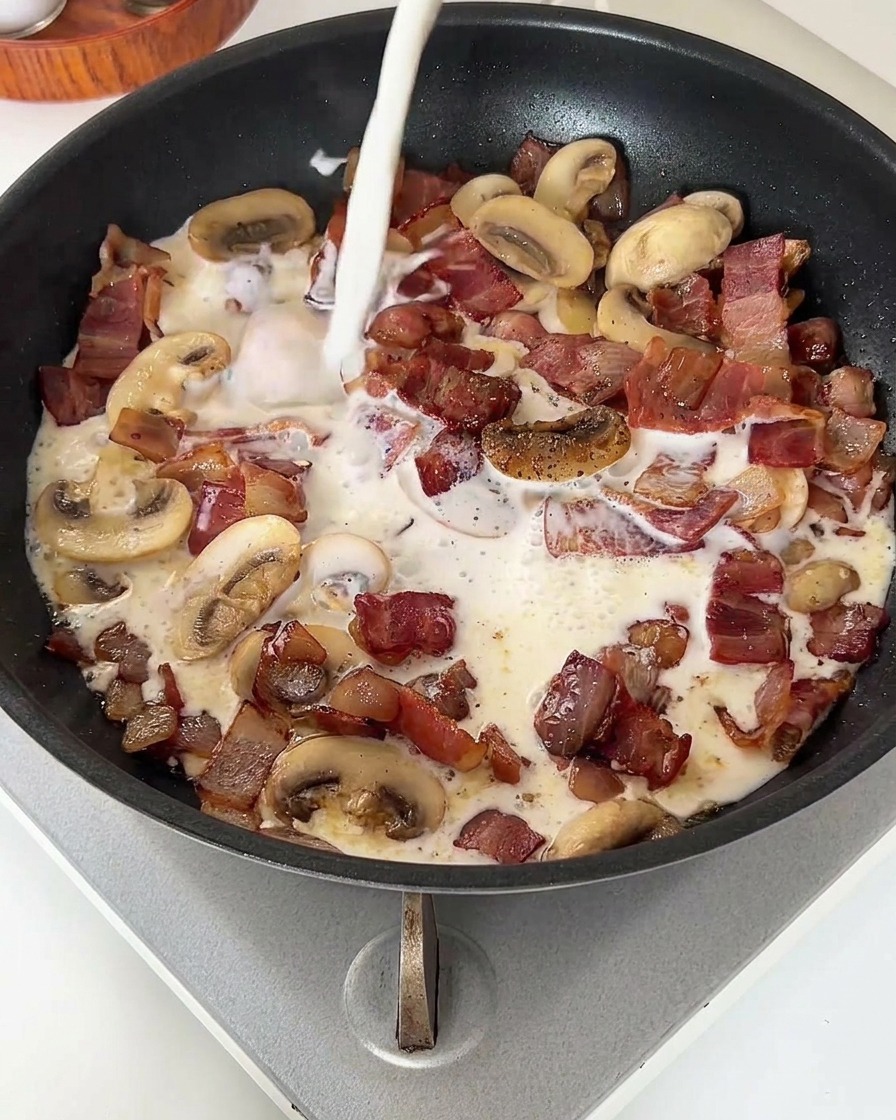 Un chorro de leche blanca cayendo sobre el sofrito de bacon y champiñones.