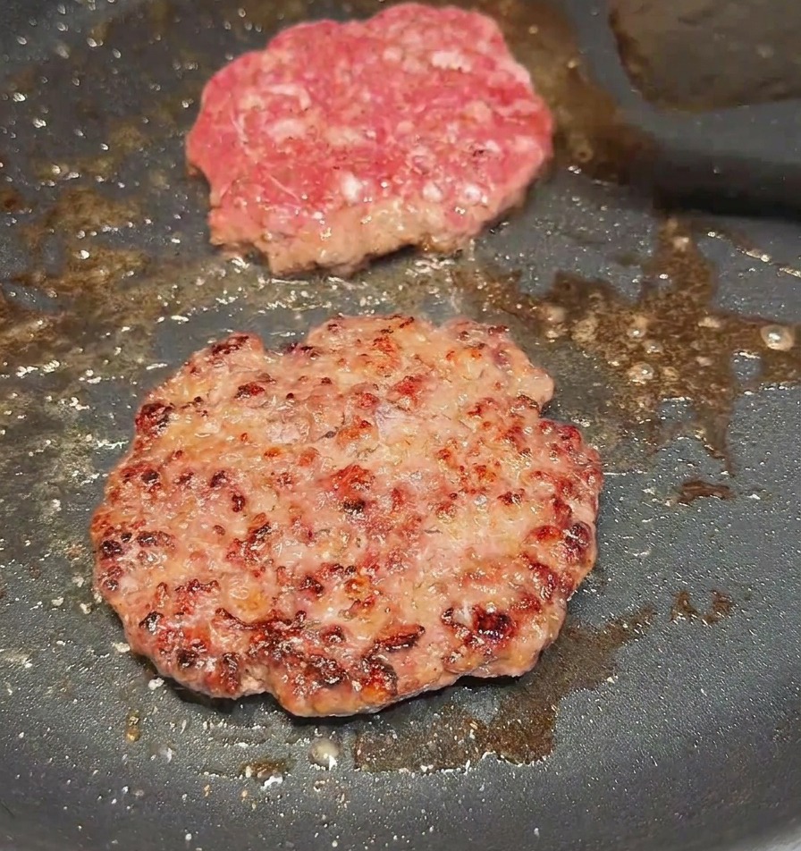 Una espátula volteando un medallón de carne para revelar una costra dorada y sellada.