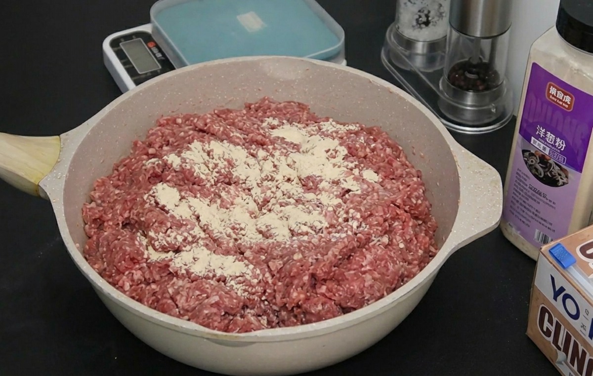 Carne molida en una bandeja con una fina capa de cebolla y ajo en polvo espolvoreados por encima.