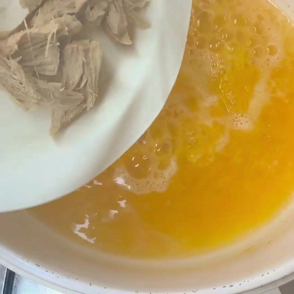 Rodajas de quingombó y carne de pato siendo añadidas en una olla de agua hirviendo.