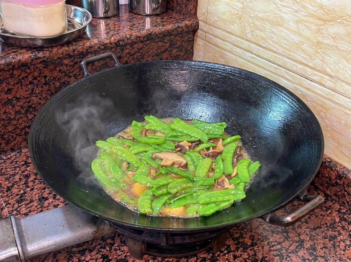 Tirabeques y salchicha de hígado de pato cocinándose en un wok con una salsa ligera.