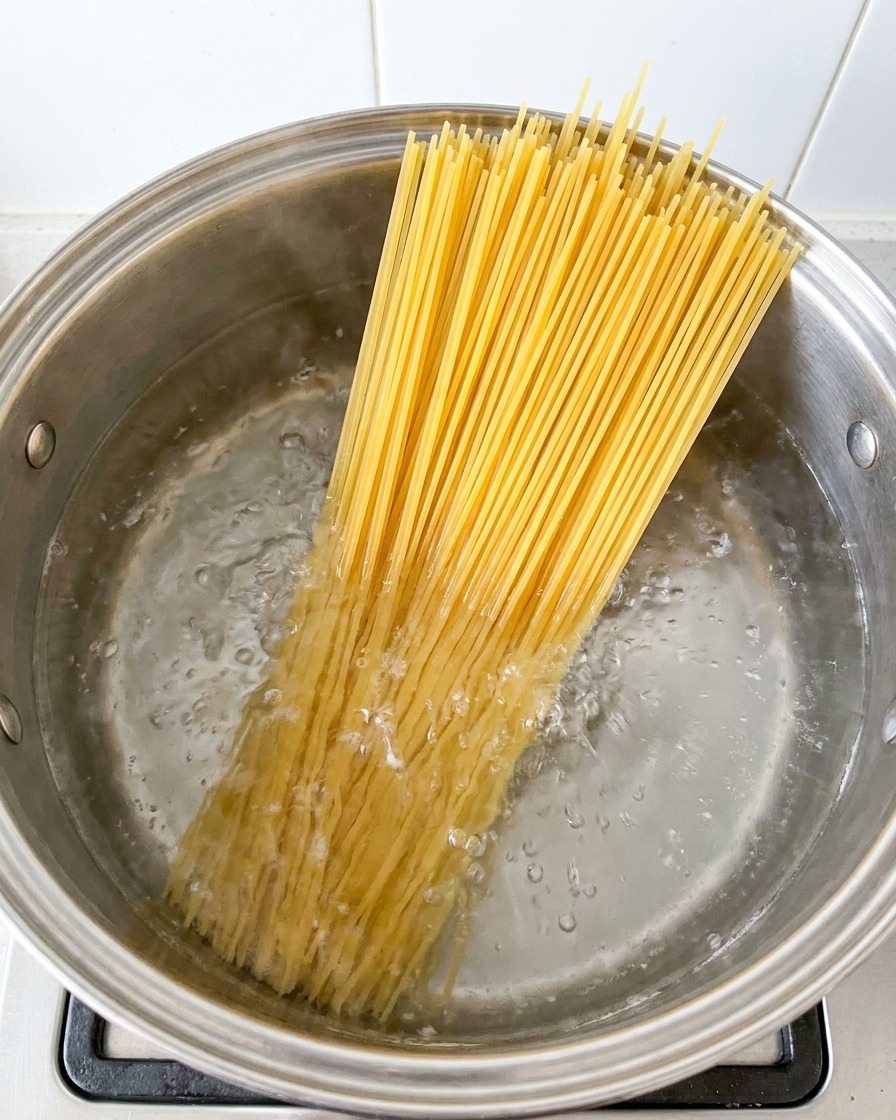 Espaguetis cocinándose en una olla grande con agua hirviendo.
