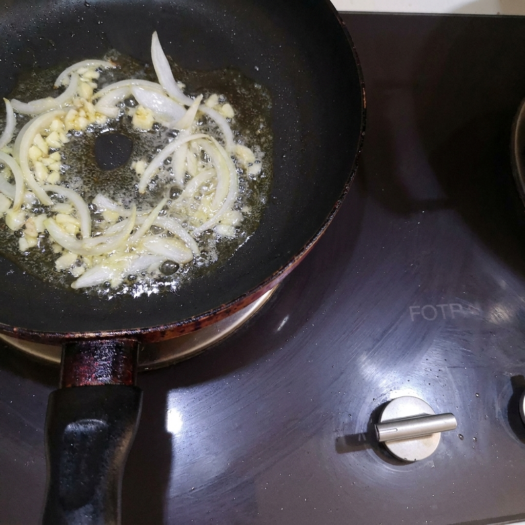 Cebolla picada y ajo picado mezclándose con la mantequilla derretida en una sartén.