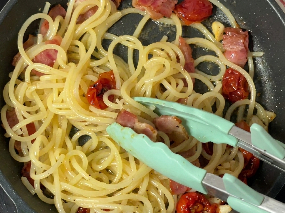 Pimienta negra recién molida sobre la pasta cocinada en una sartén.