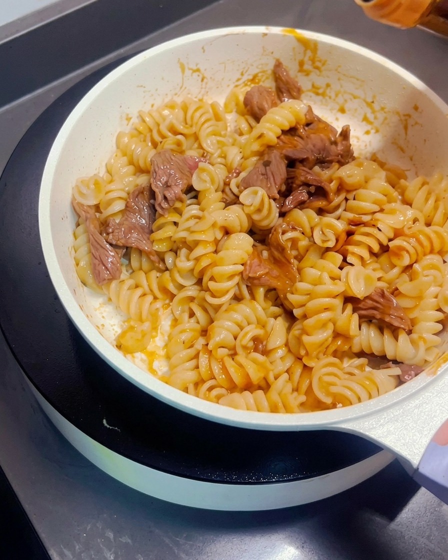Salsa de soja oscura siendo rociada sobre la pasta salteada y la ternera.