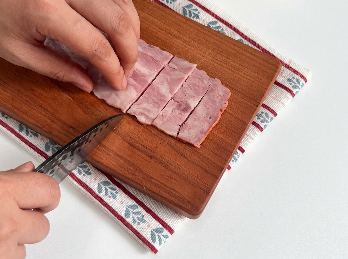 Lonchas de tocino crudo dispuestas sobre una tabla de madera.