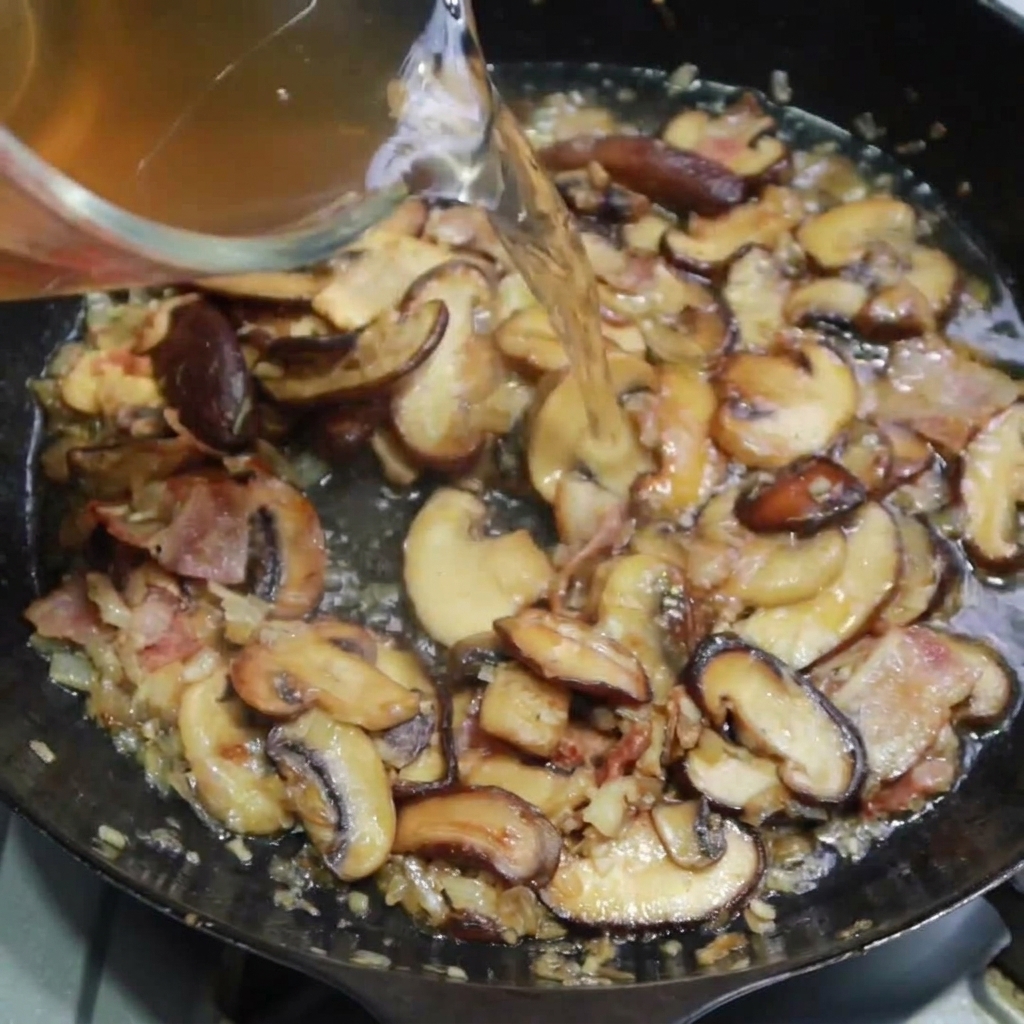 Caldo de pollo vertiéndose en la sartén para hervir a fuego lento con la mezcla.