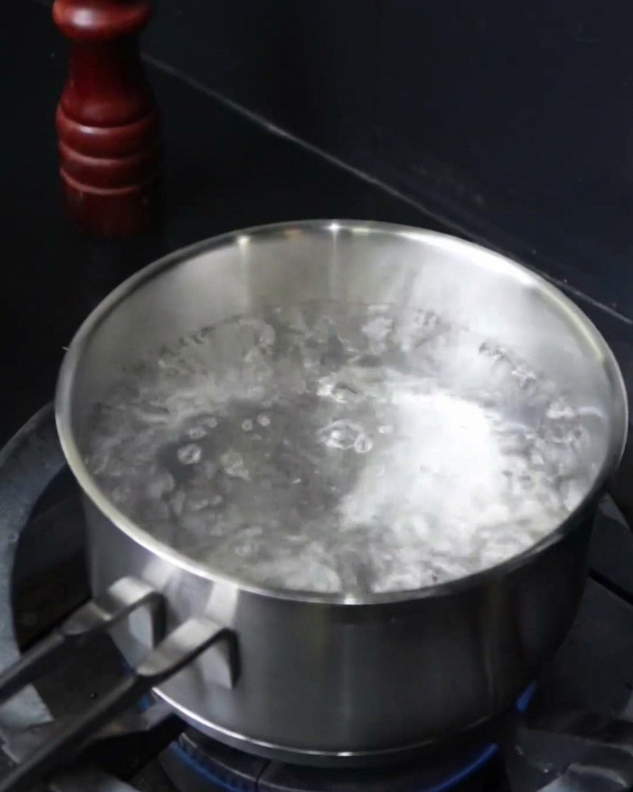 Espaguetis sumergiéndose en una olla con agua hirviendo salada.