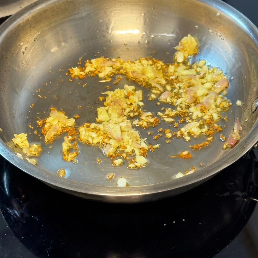 Almejas frescas y crudas siendo añadidas a la sartén con la cebolla y el ajo sofritos.