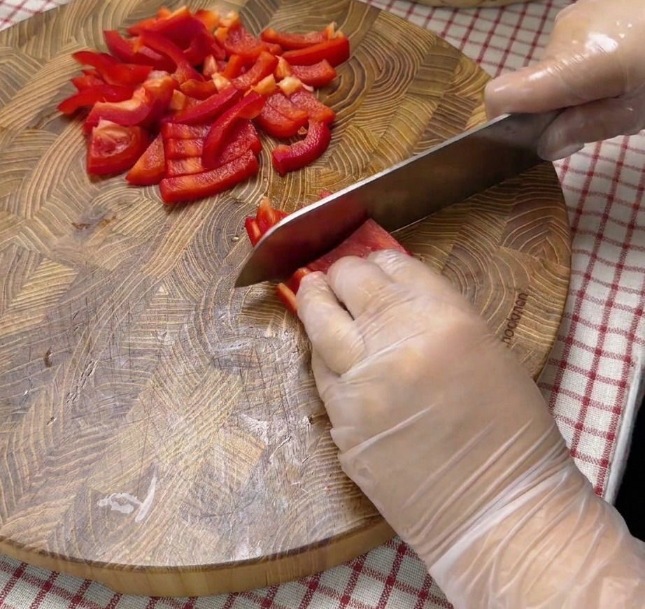 Trozos de pimiento rojo picado sobre una tabla de cortar de madera.