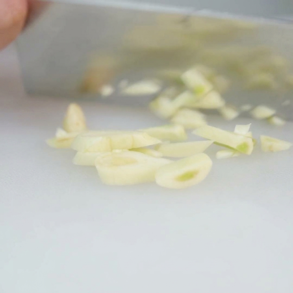 Tiras de bacon siendo cortadas en trozos de 1 cm y colocadas en un bol metálico.