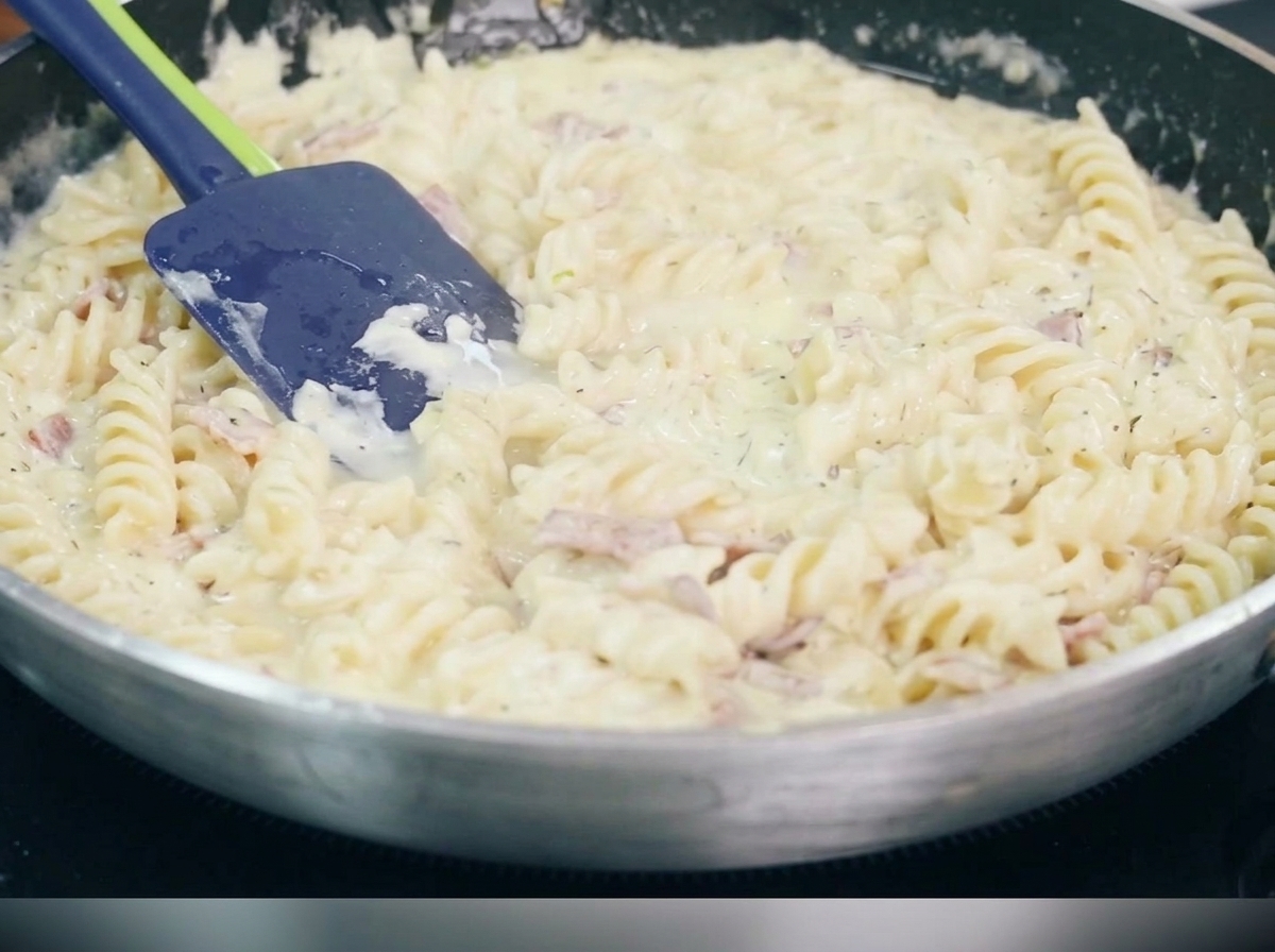 Trozos de bacon dorado y crujiente friéndose en una sartén.