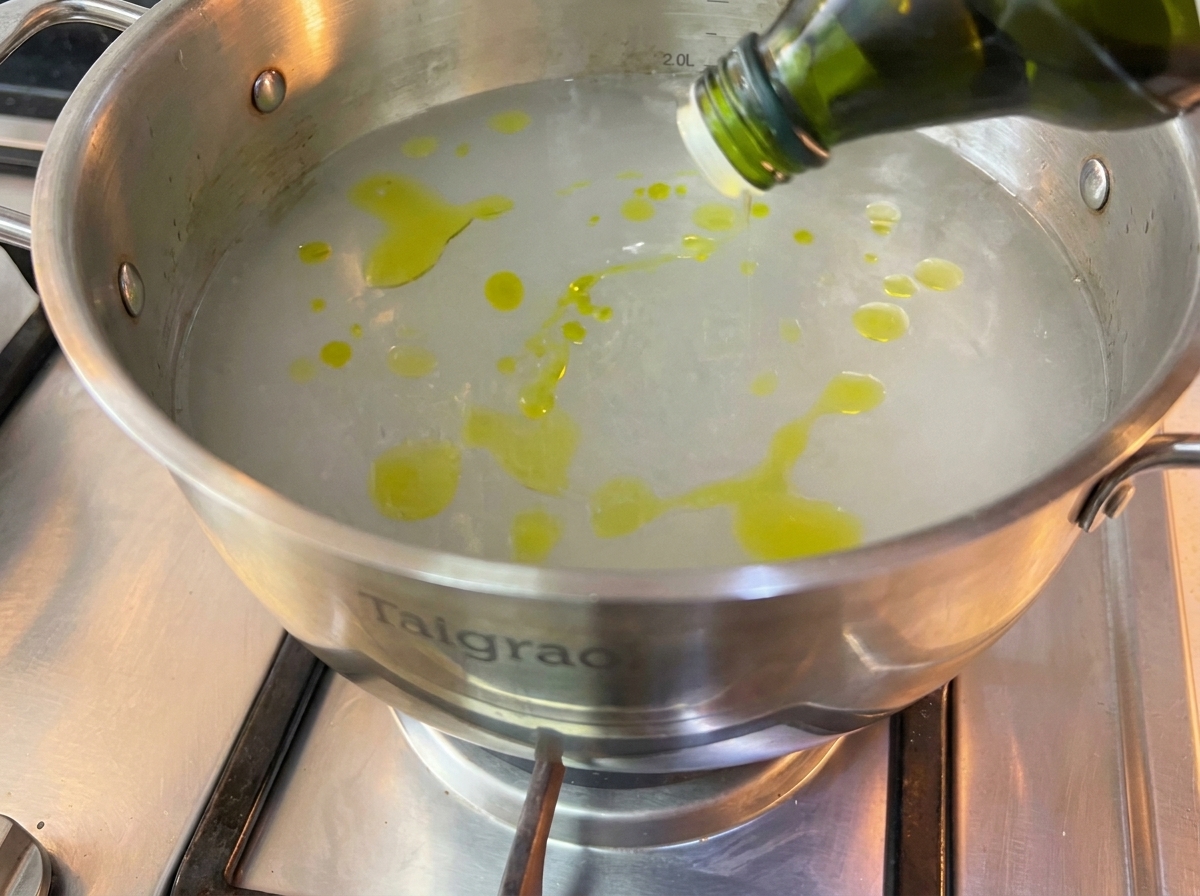 Fideos de espagueti secos sumergidos en una olla grande con agua hirviendo.