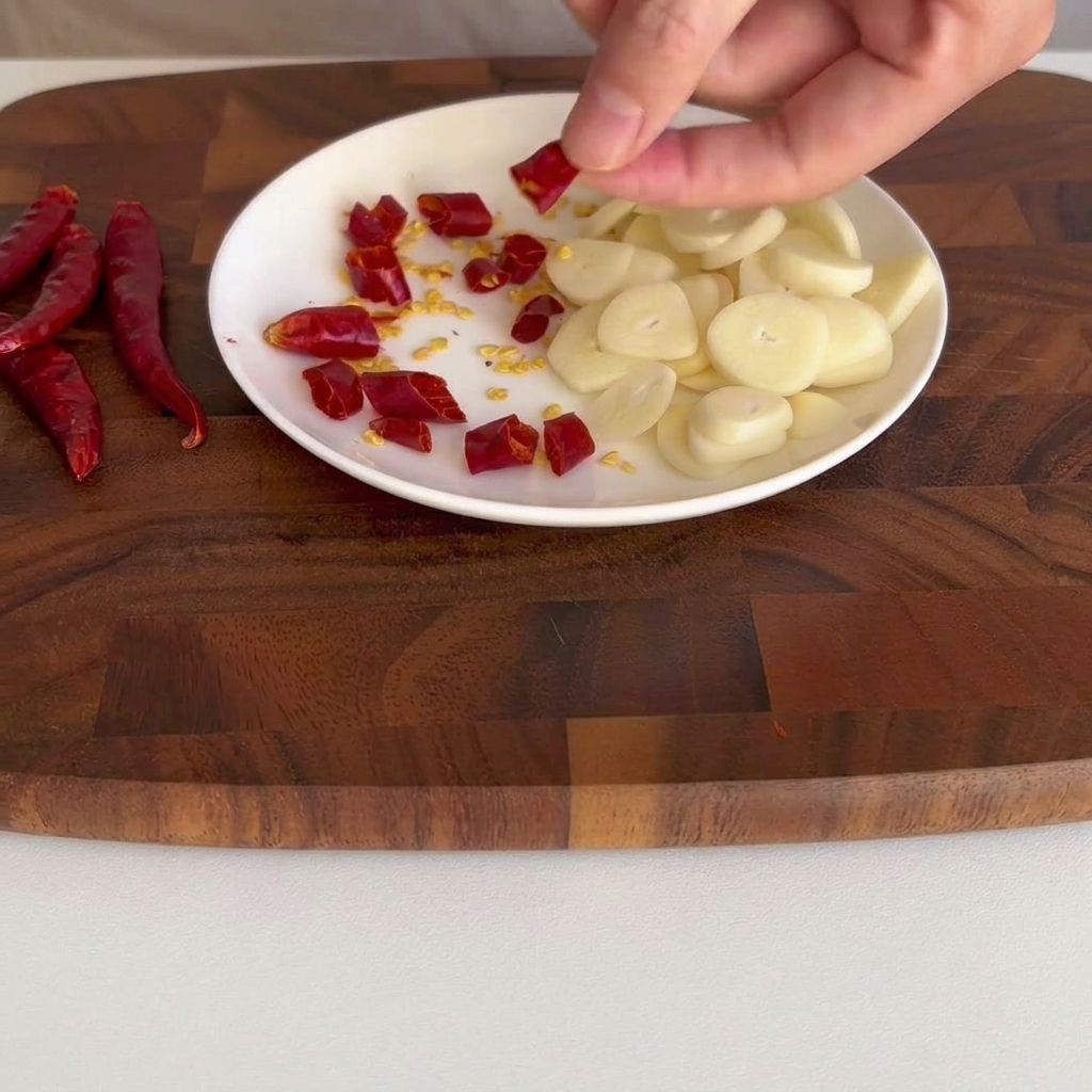 Pequeños trozos de chile rojo seco esparcidos sobre un plato blanco pequeño.