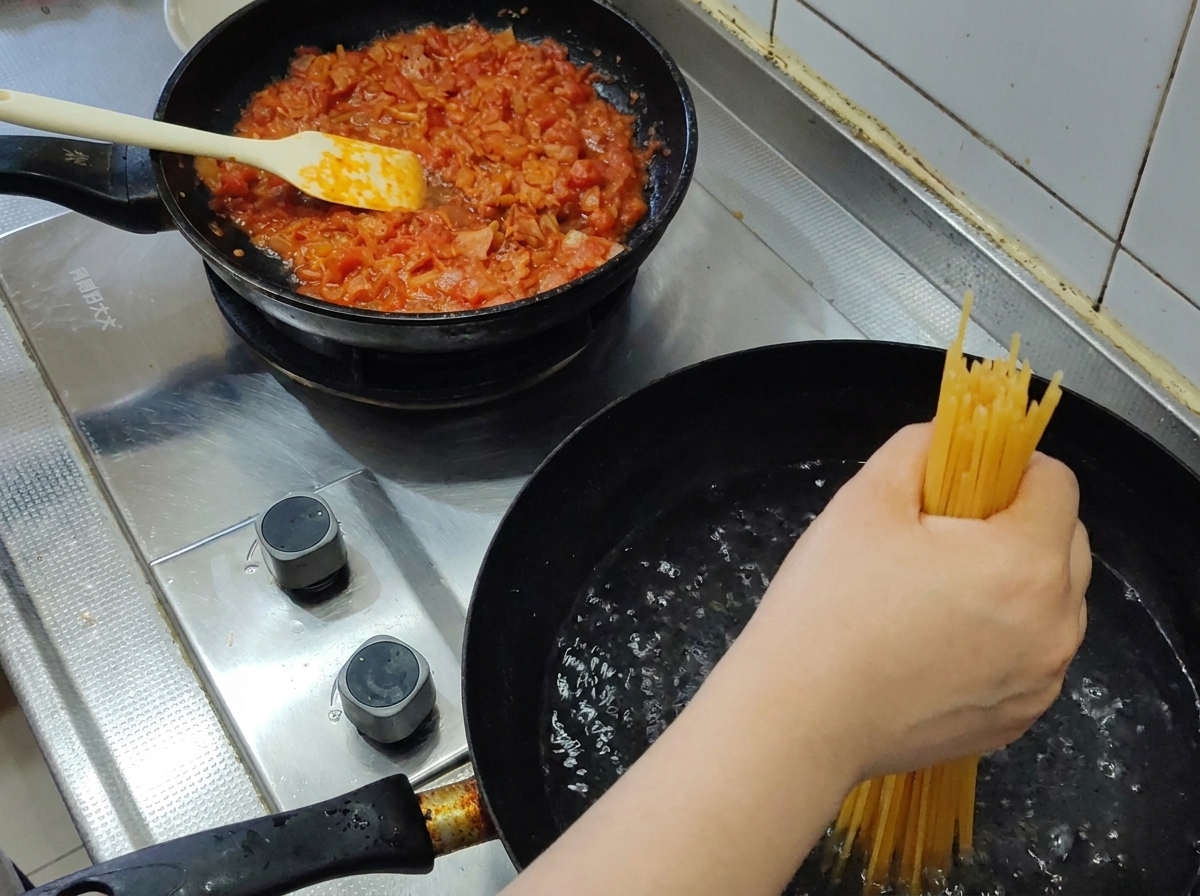 Un puñado de espaguetis secos siendo sumergidos en una olla de agua hirviendo.