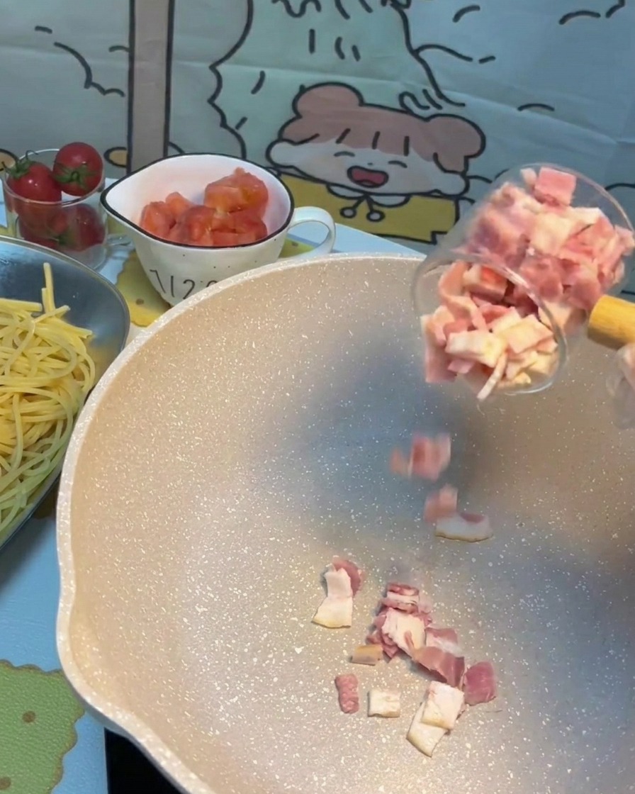 Trozos de tocino chisporroteando y dorándose en una sartén caliente.