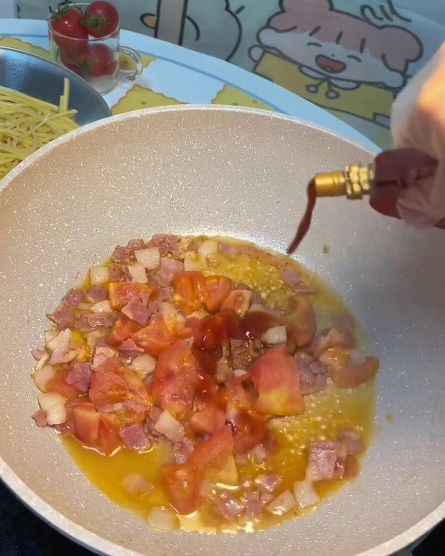 Salsa de soja, salsa de tomate y azúcar siendo vertidas en la sartén con tocino y tomates.