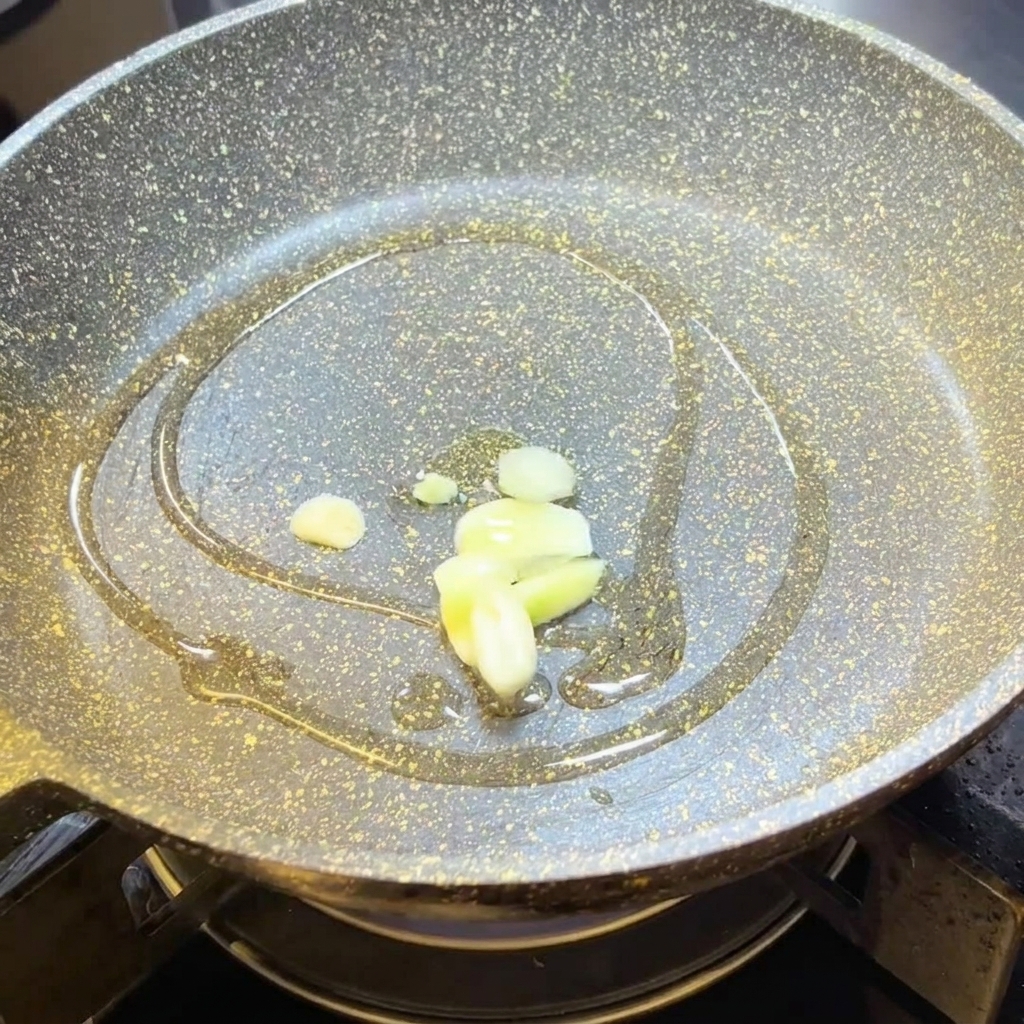 Láminas de ajo friéndose en aceite de oliva caliente en una sartén.