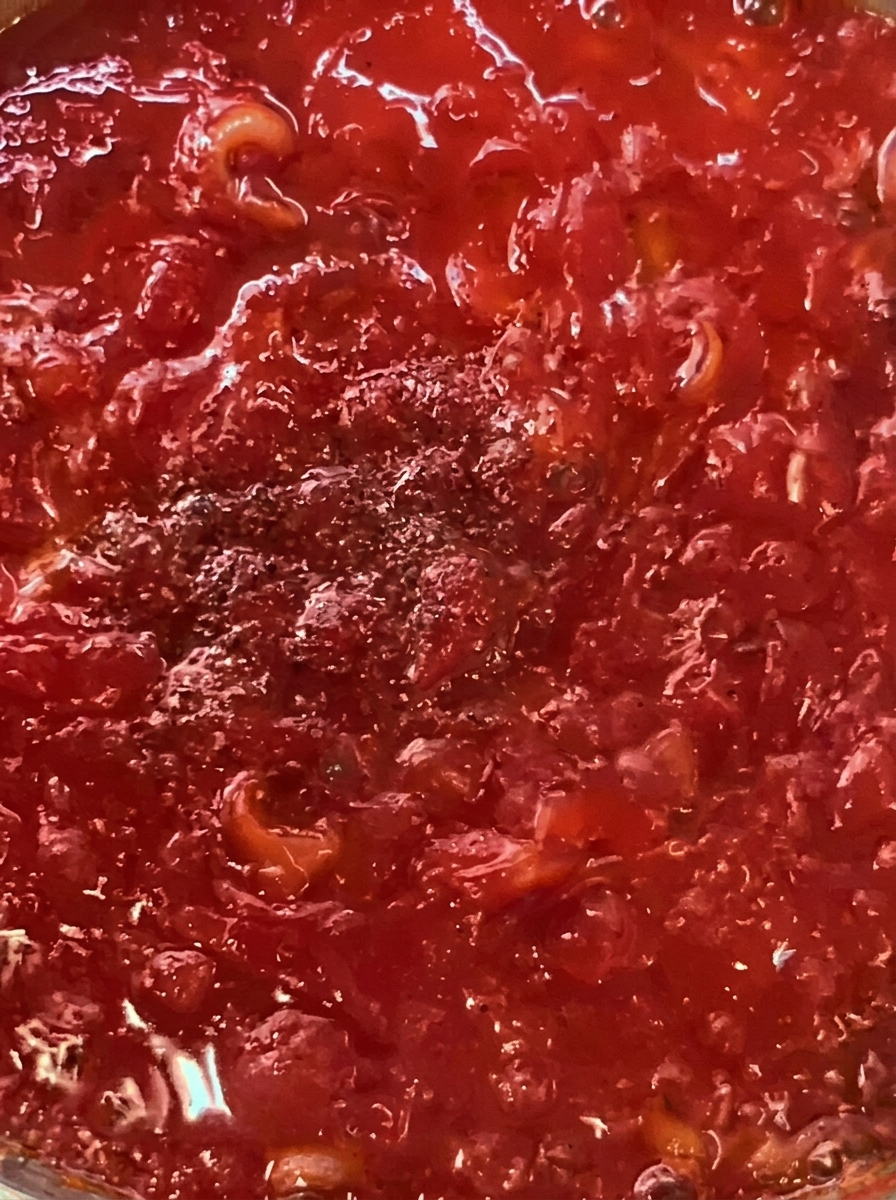 Tiras de bacon y tomates cherry cocinándose en una sartén con aceite de oliva.