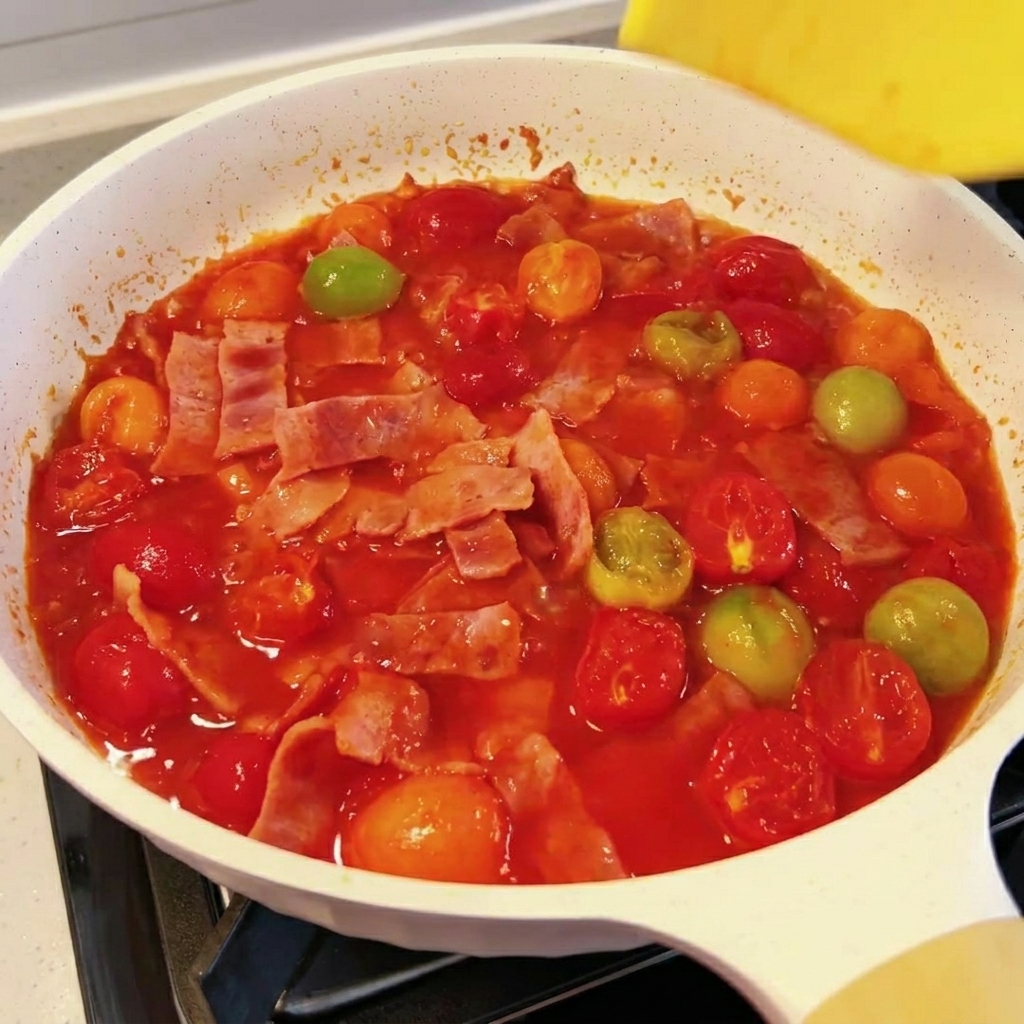 Una loncha de queso derritiéndose en la salsa de tomate y bacon.