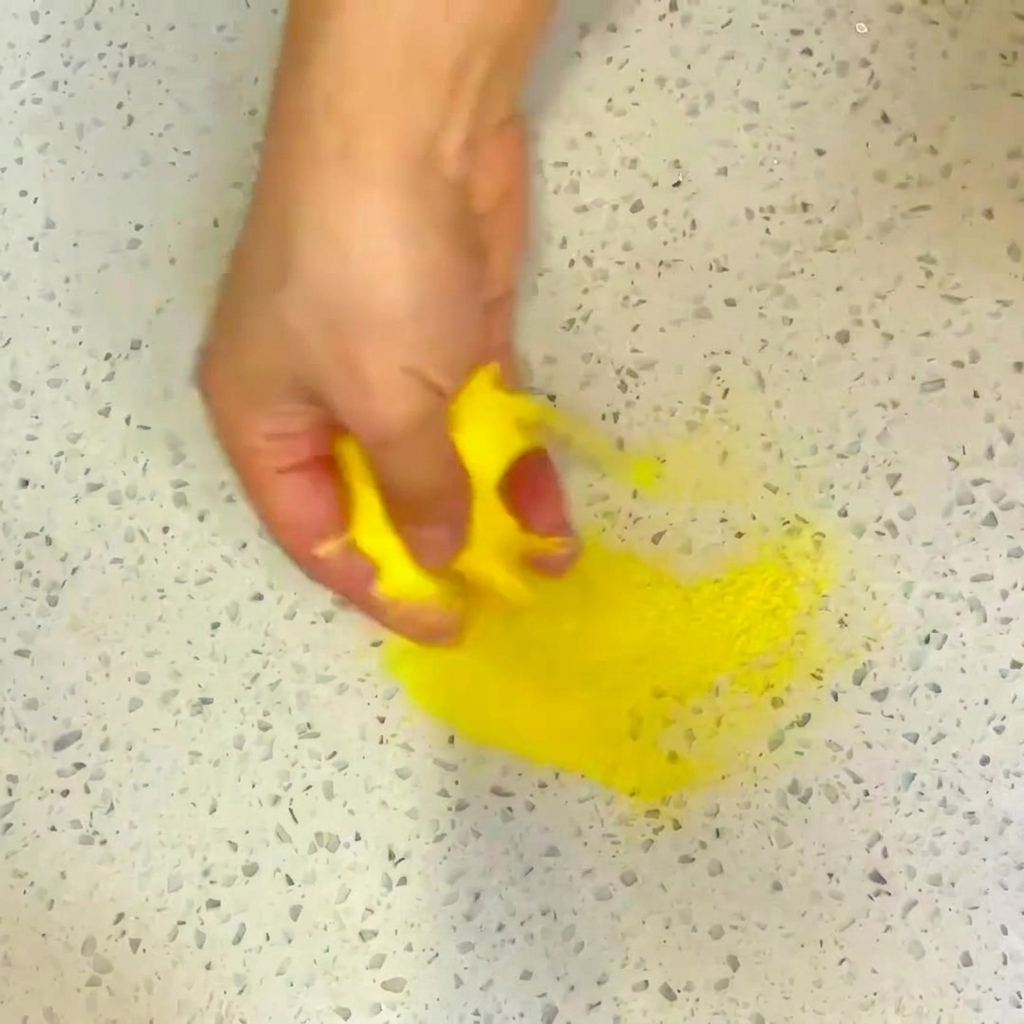 Un pincel aplicando una capa de aceite en la base de una sartén de acero inoxidable.