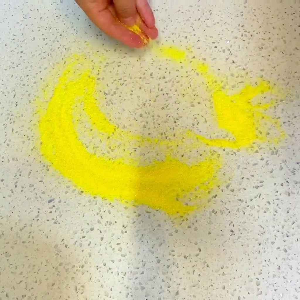 Una salsa de menta a base de hierbas siendo rociada sobre la capa de salsa de tomate en la pizza.