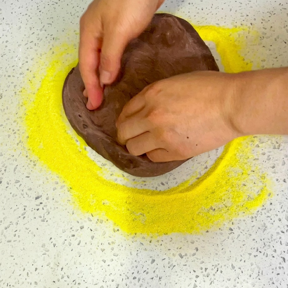 Queso rallado siendo espolvoreado uniformemente sobre los ingredientes de la pizza ensamblada.