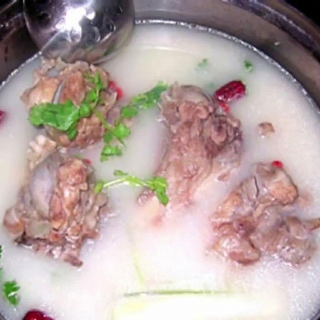 Varios huesos grandes de cerdo sumergidos en un caldo opaco y lechoso, decorado con hierbas frescas.