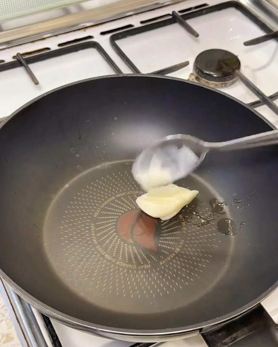 Una cucharada de manteca de cerdo blanca derritiéndose en una sartén negra caliente.
