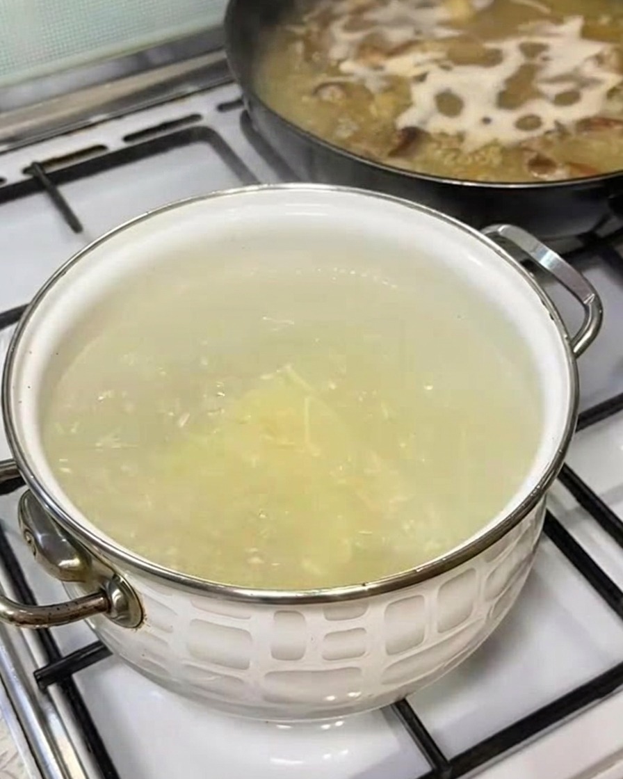 Un manojo de fideos de ramen frescos siendo introducidos en una olla de agua hirviendo.