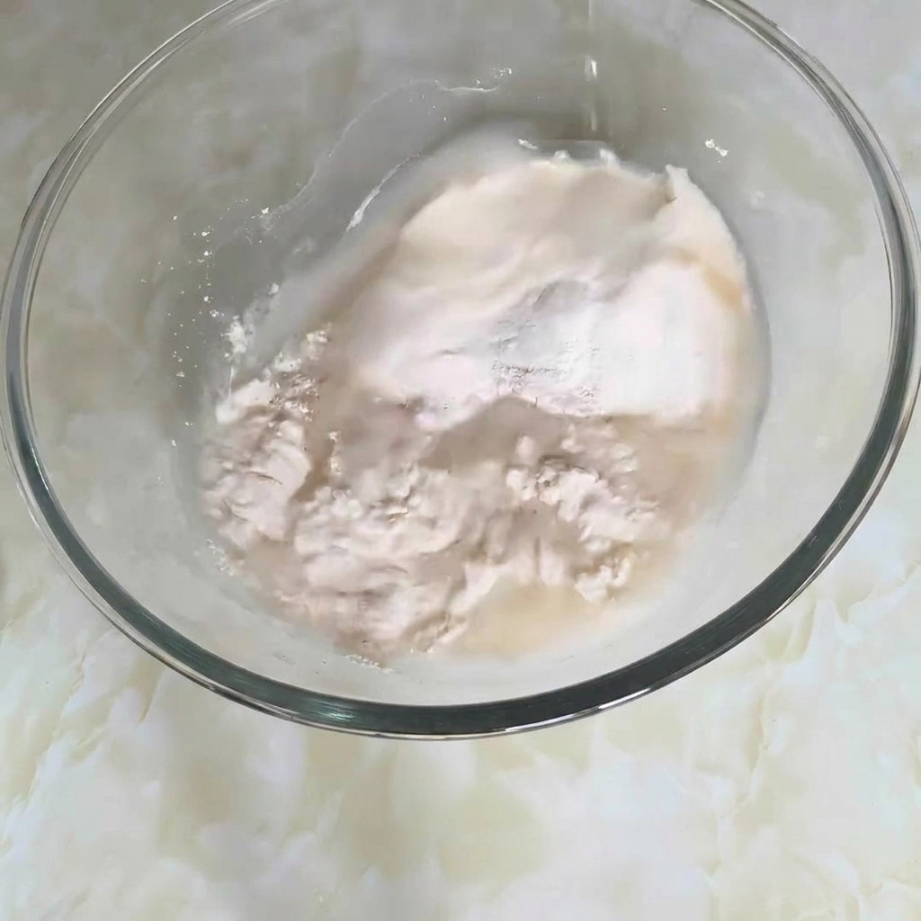 Un primer plano de un bol de mezclas con harina, agua y otros ingredientes siendo removidos para formar una masa.