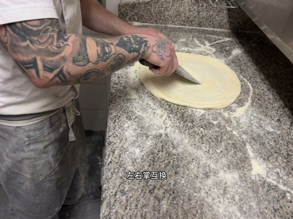 Chef realizando la técnica de estiramiento rítmico sobre la masa de pizza.