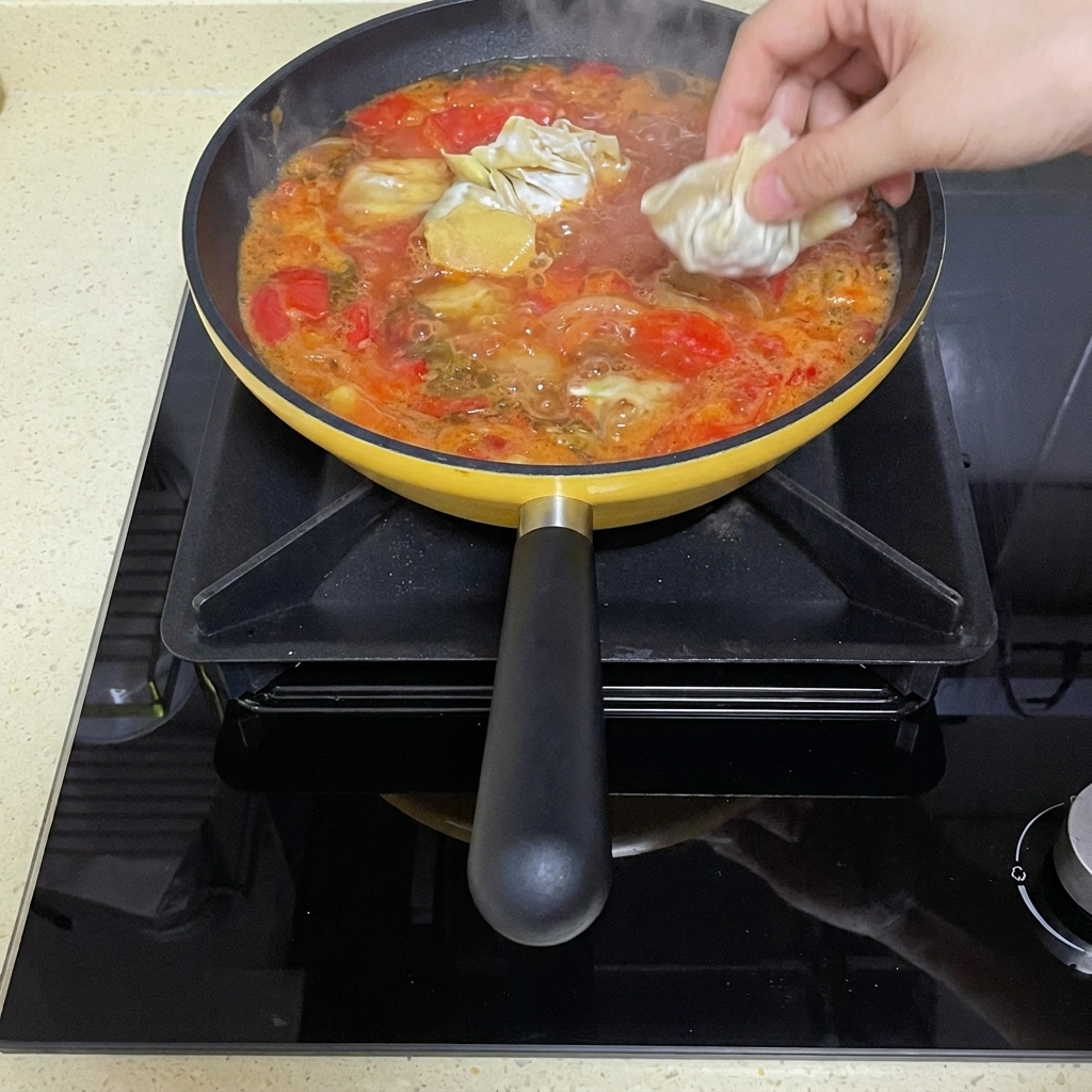 Wontons crudos doblados que se sumergen en el caldo de tomate a fuego lento.