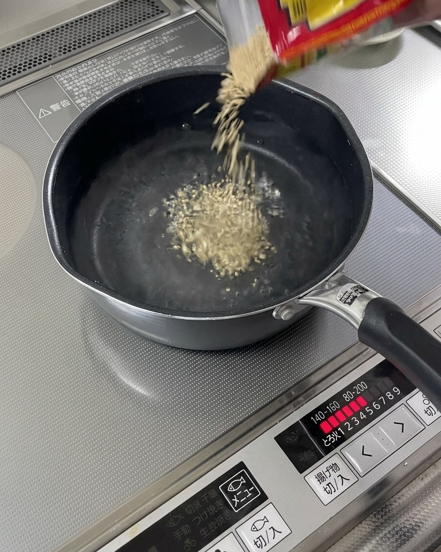 Semillas de sésamo tostadas cayendo en una olla de líquido hirviendo.