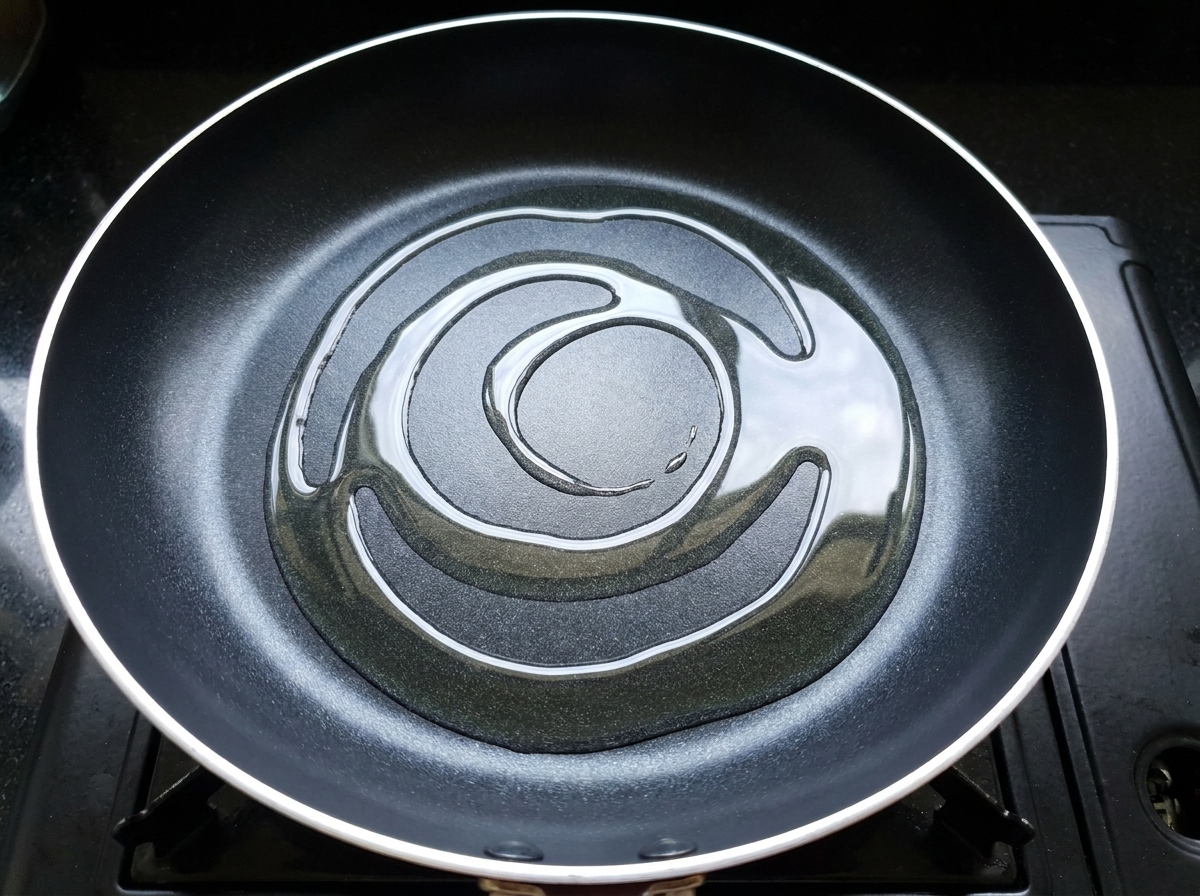 Trozos de pollo marinado siendo añadidos a una sartén caliente con aceite.