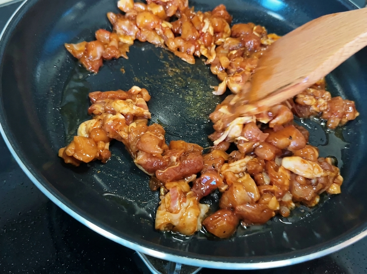 Trozos de pollo salteados en una sartén, mostrando una caramelización de color marrón dorado.