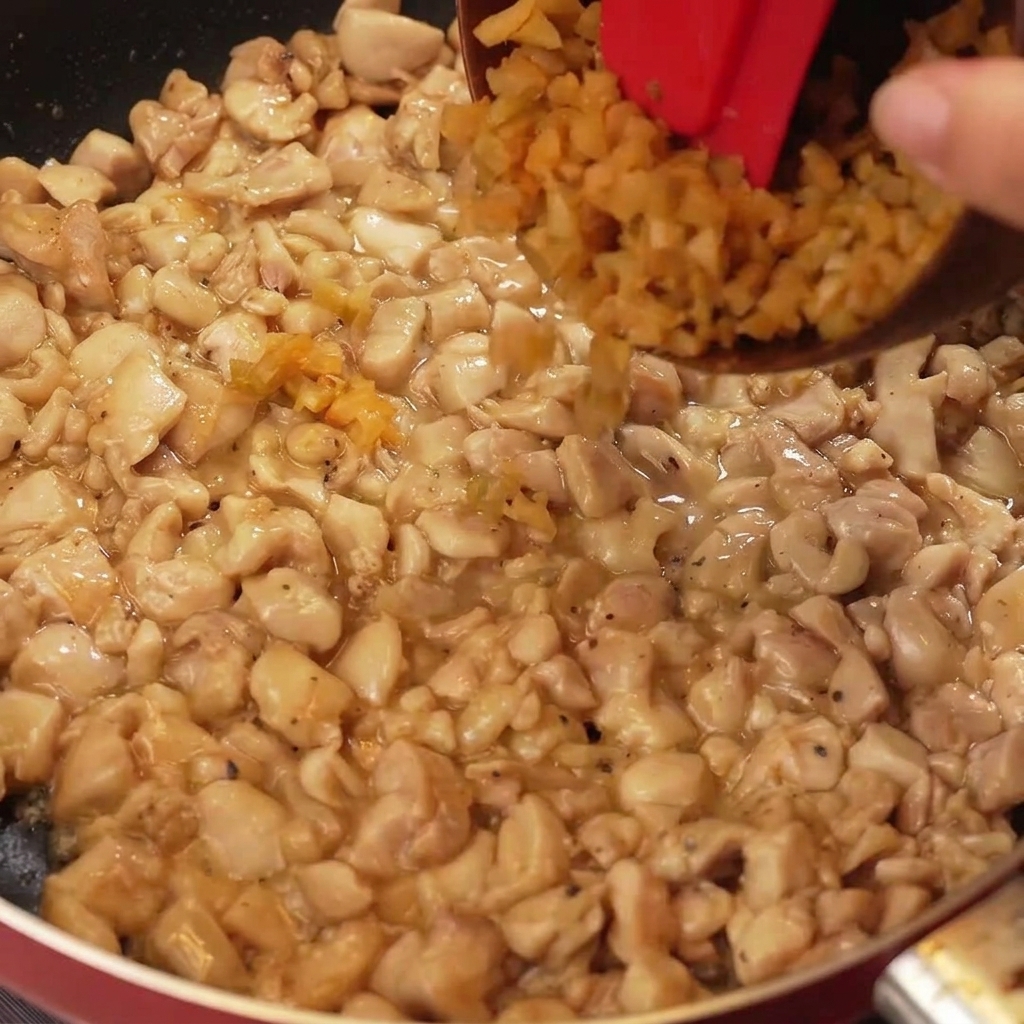 Mostaza encurtida picada y partes blancas de cebolleta añadidas a una sartén con pollo dorado.