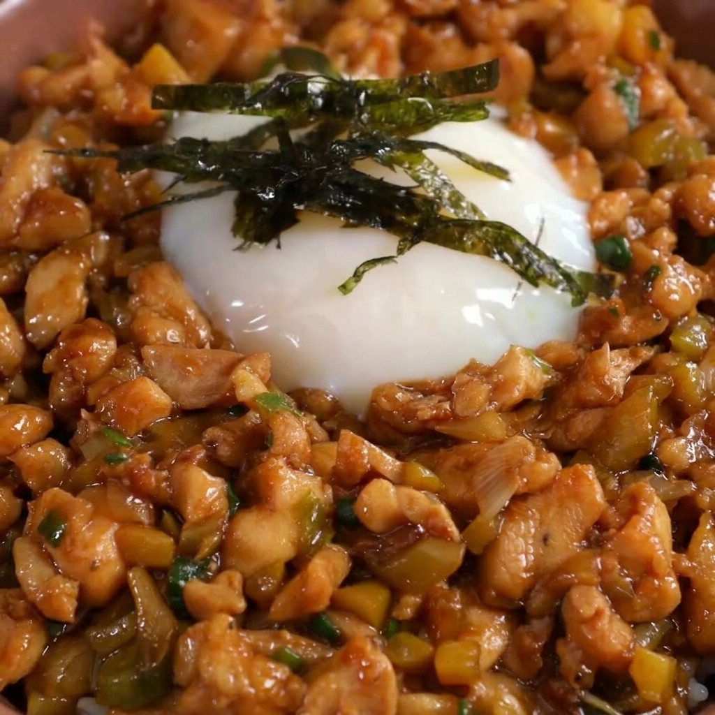 Alga nori cortada finamente colocada encima de un huevo onsen en un tazón de pollo y arroz.