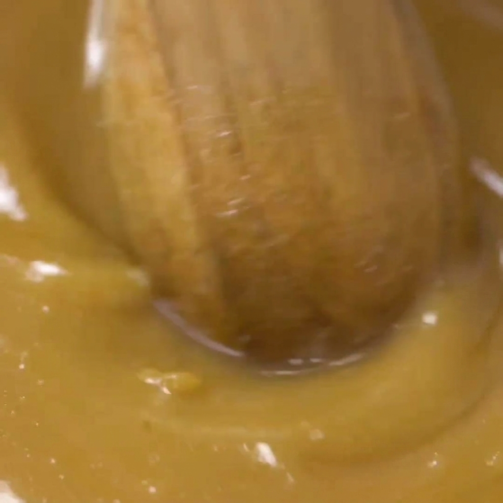 Una cuchara de madera mezclando la salsa de miso en un cuenco.