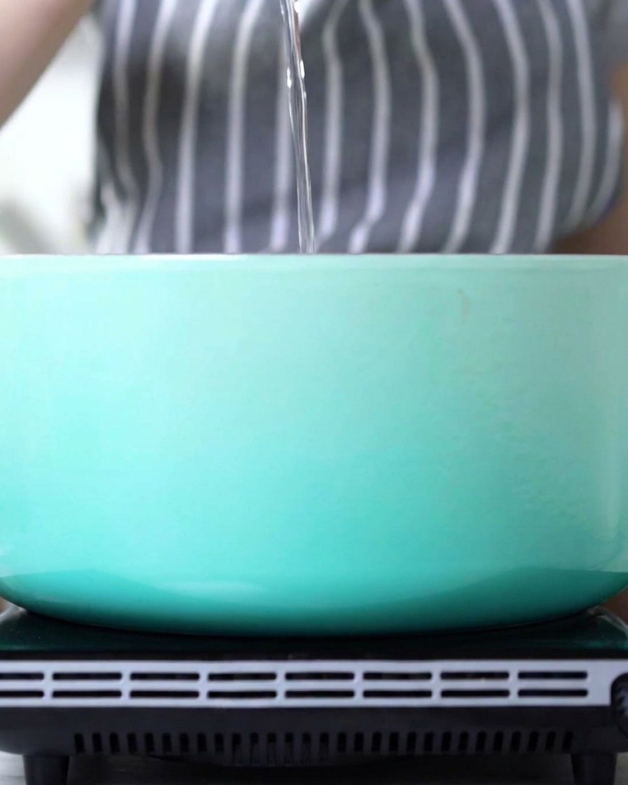 Un chorro de aceite siendo vertido en una olla esmaltada azul claro.