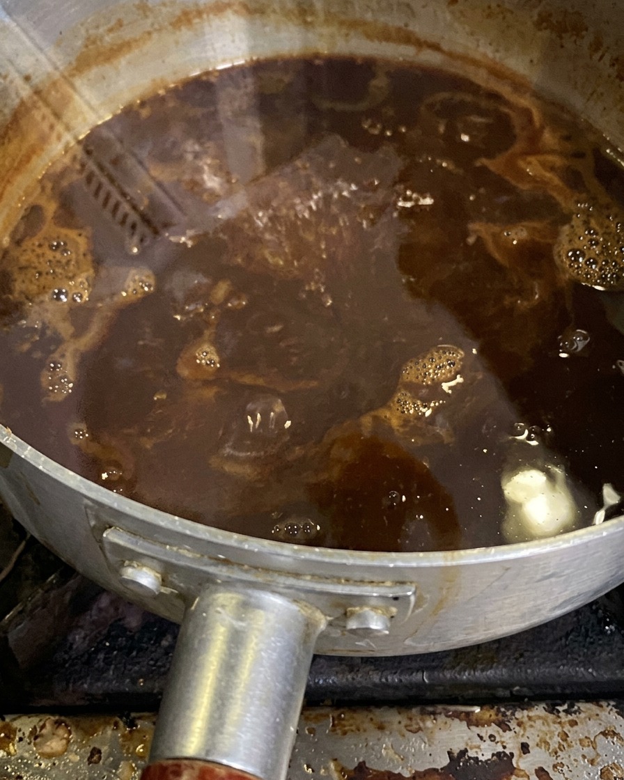 La salsa de miso burbujeando suavemente en una cacerola mientras hierve a fuego lento y se reduce.
