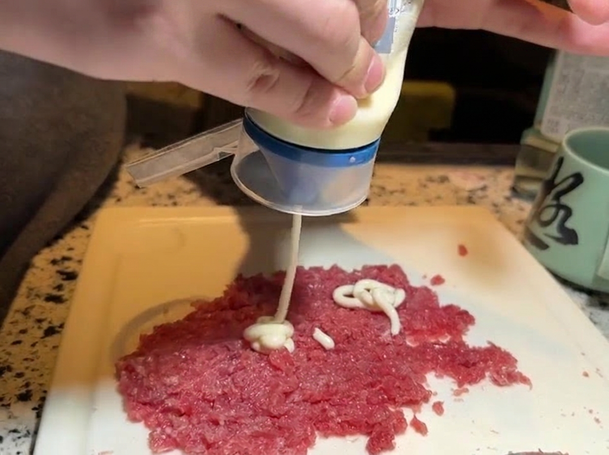 Aplicando mayonesa sobre una porción de atún picado.