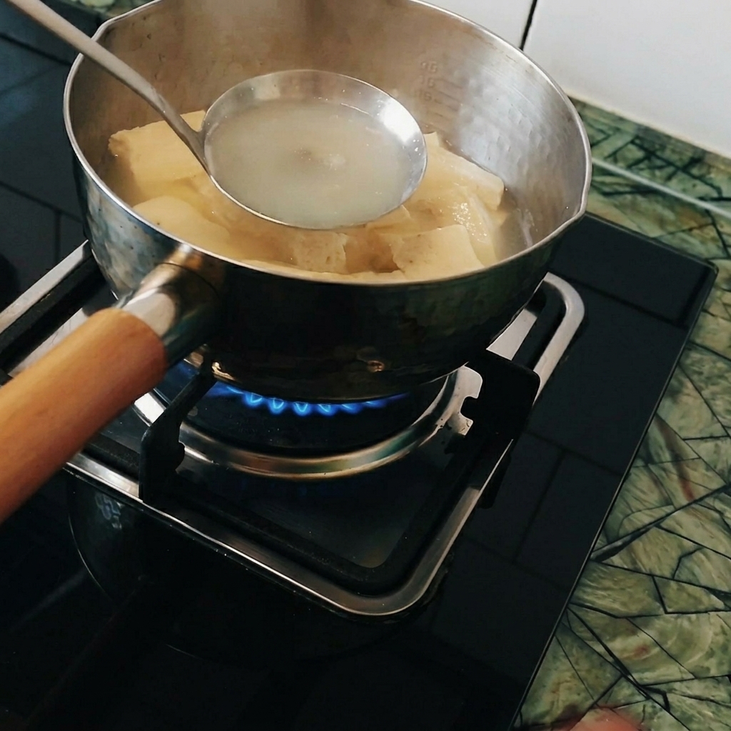 Trozos de curry siendo disueltos en un cucharón dentro de la olla de agua hirviendo.